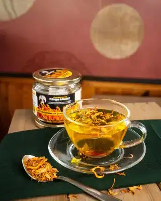 Clear glass cup with floral tea and saucer, featuring a vibrant yellow-orange hue from the dried petals.
